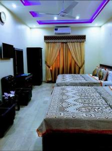 a bedroom with two beds and a stage with purple lights at Hotel Moon Light view in Lahore