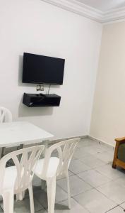 a white table with two white chairs and a tv on a wall at La vague in Île Pilau