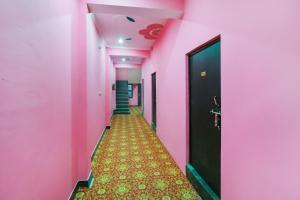 a corridor with pink walls and a hallway with a door at Hotel O Rajdhani Hotel in Kākori