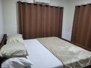 a bed in a bedroom with a brown curtain at Serenity Appartementen 2 in Paramaribo