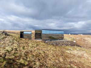 a glass house on a hill in a field at ÖÖD Hekla Horizon - Mirror Houses in Hella