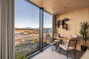 a room with a table and chairs and large windows at ÖÖD Hekla Horizon - Mirror Houses in Hella