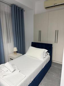 a bedroom with a large bed with a blue headboard at Nivro in Delvinë