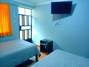 a bedroom with two beds and a television on the wall at El REFUGIO DE MIS SUEÑOS in Yungay