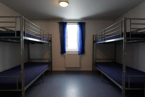 a room with three bunk beds and a window at Kammak Hostel Sisimiut in Sisimiut