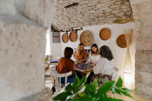 Drei Frauen sitzen an einem Tisch in einem Raum mit Weinfässern. in der Unterkunft Naki in Bosa + 23 Fotos
