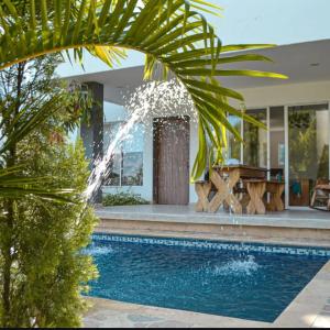 a swimming pool with a fountain in front of a house at Cabaña Villa July in Moñitos