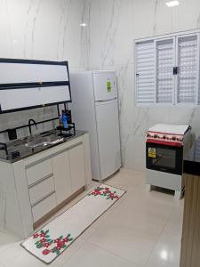a white kitchen with a refrigerator and a stove at Pousada Do Goiano in Manhã