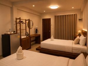 a hotel room with two beds and a mirror at Na Sukhothai Hotel in Sukhothai