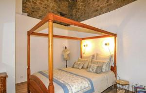 a bedroom with a wooden canopy bed with pillows at Apaisante Villa Piscine in Taulis