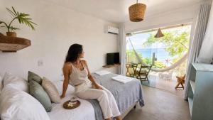a woman sitting on a bed in a room with a window at Monkey beach agroturismo in Gamboa
