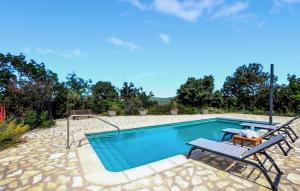 a swimming pool with two chairs and a table at Charmante Villa Piscine in Taulis