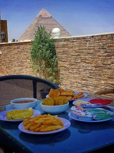 a blue table with plates of food and the pyramid at Casa pyramids hotel in Cairo
