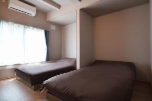 two beds in a small room with a window at plus81 OTARU Entire House 9min Walk from Minami Otaru Station in Otaru