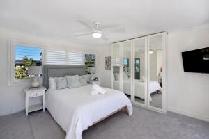 a white bedroom with a bed and a tv at The River Retreat in Sussex Inlet +40 photos