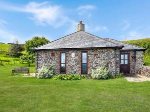 a stone house with a bench in the grass at Beehive Cottage Culbone in Porlock