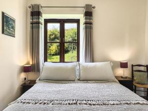 a bedroom with a bed and a window at Beehive Cottage Culbone in Porlock