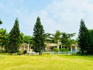 a group of trees in a field with a house at Solmist Villa in Hòa Bình