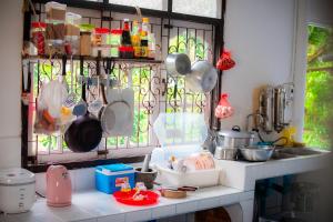 a kitchen with pots and pans hanging from a wall at Honey You HOSTEL in Ban Khlong Mat