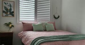 a bed with pink and green pillows and a window at Marigold House in Rockville +6 photos