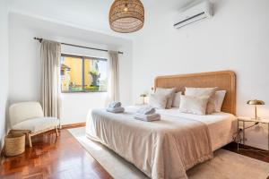 a bedroom with a bed and a chair and a window at Vilamoura Escape with Private Pool in Vilamoura +26 photos