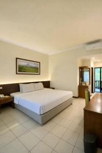 a bedroom with a large bed and a desk at Grand Whiz Hotel Trawas Mojokerto in Trawas +25 photos