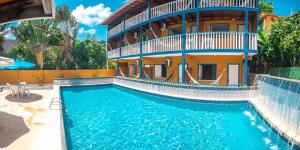 a house with a swimming pool in front of a building at Brisa do Caitá Praia Hotel in Morro de São Paulo