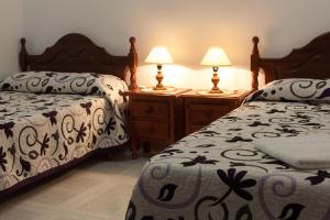 1 dormitorio con 2 camas y 2 mesitas de noche con lámparas en Extrenatura Alojamiento Apartments, en Villafranca de los Barros