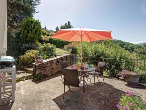 a table with a red umbrella in a garden at Gîte au cœur d'un village médiéval, charme et confort moderne - FR-1-496-125 in Chagnon