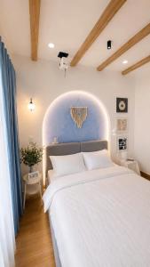 a bedroom with a large white bed with a blue wall at LàMin Homestay in Ấp Long Ðại +17 photos