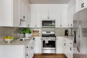 a white kitchen with white cabinets and a sink at Modern Designer Home with Shared Pool in Austin