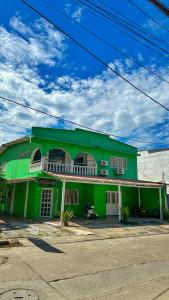 a green building with a street in front of it at Hotel Porton De Oriente in Puerto Triunfo