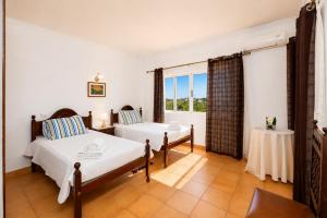 a bedroom with two beds and a table and a window at Villa Sol Nascente in Porches +16 photos