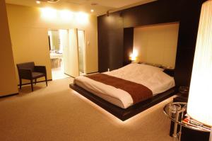 um quarto com uma cama e uma cadeira em Blue Hotel Octa (Adult Only) em Sapporo