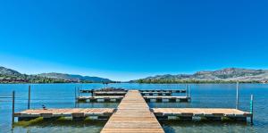 a dock on a lake with mountains in the background at Luxury Condo 2Bed, 1Bath, Pool, Hot Tub, Beach, Golf in Osoyoos