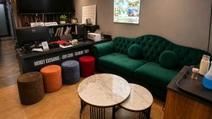 a living room with a green couch and stools at Awesome Hanoi Hostel & Travel in Hanoi