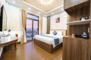 a bedroom with a bed and a desk and a window at Winston Hotel Riverside in Ho Chi Minh City