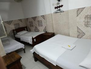 a small room with two beds in a room at Hotel La Palma Girardot in Girardot
