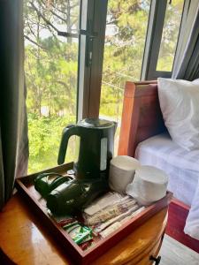 a green coffee maker on a table next to a window at Mây Măng Đen Villa in Chương Nghĩa