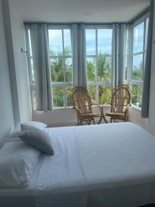a bedroom with a bed and two chairs and windows at Hotel La Cima in Arboletes