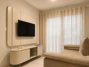 a living room with a television and a couch at Apartamento Flores do Bosque in Garanhuns