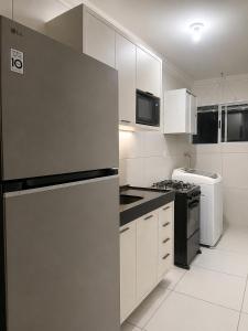 a kitchen with white cabinets and a refrigerator at Apartamento Flores do Bosque in Garanhuns