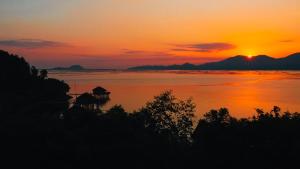 a sunset over a lake with a house in the water at Vedana Lagoon Resort & Spa in Hue