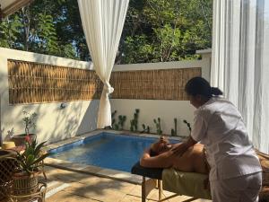 a woman giving a man a massage by a swimming pool at Villa Sea La Vie Private pool in Gili Meno