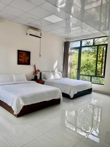 a bedroom with two beds and a large window at Mây Măng Đen Villa in Chương Nghĩa