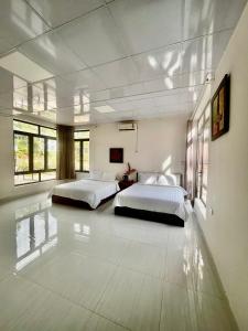 two beds in a large room with white walls at Mây Măng Đen Villa in Chương Nghĩa +23 photos