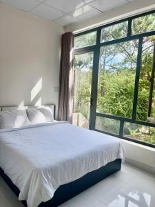 a bedroom with a bed and a large window at Mây Măng Đen Villa in Chương Nghĩa
