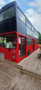 a red double decker bus parked on a wooden deck at insolite bus anglais le Buckinghambus in Saint-Philbert-sur-Risle +5 photos