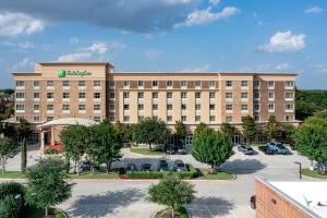 an exterior view of a hotel with a parking lot at Holiday Inn Garland by IHG in Garland