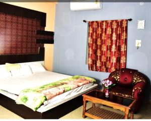 a bedroom with a bed and a chair and a window at Hotel Royal Palace Dharamgarh in Dharamgarh